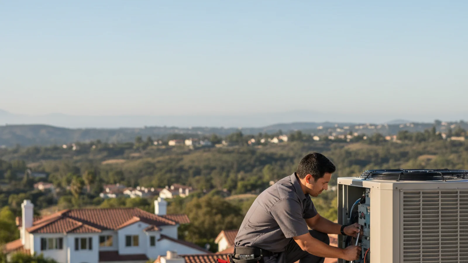 HVAC technician inspecting an outdoor condenser unit at a rural Bonsall California estate property, dry inland hills and avocado grove visible in the background